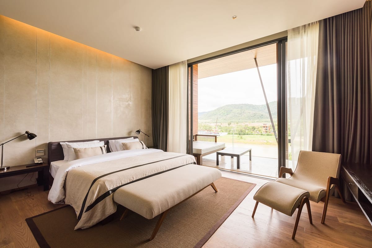 Une chambre d’hôtel moderne, dotée d’un grand lit, d’un bureau, d’une chaise et offrant une vue sur l’extérieur.