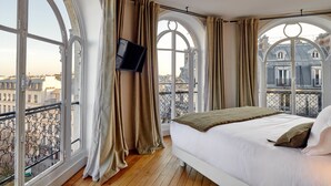 A bedroom with a large bed, a flat-screen TV mounted on the wall, and large windows with curtains. - Tinah Paris - Reaumur Montorgueil (Paris)
