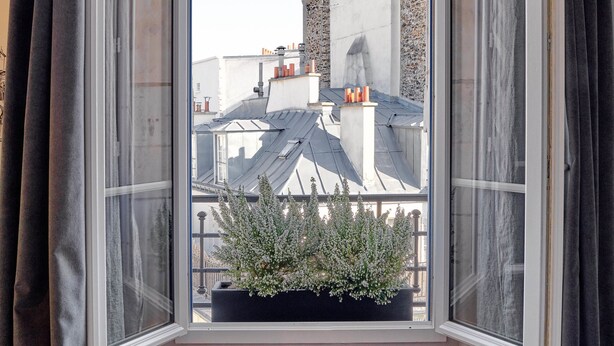 A room with a bay window, wooden flooring, and a view of neighboring buildings. - Tinah Paris - Reaumur Montorgueil (Paris)