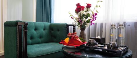 A green sofa, a vase with flowers, and a tray with items.