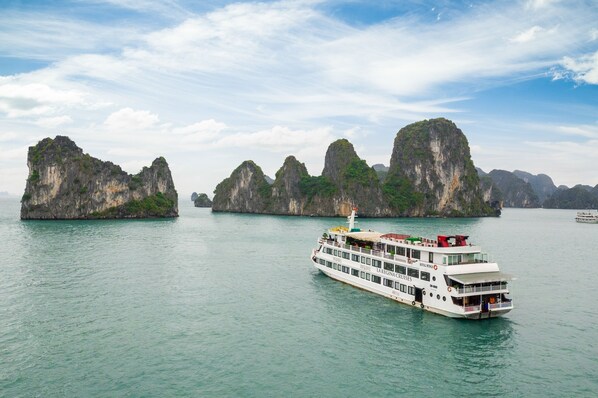 A cruise ship named LAREGINA CRUISES sailing near limestone karsts. - La Regina Royal Cruise (Ha Long)