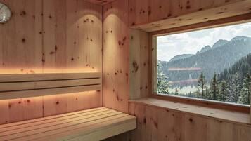 Una sauna de madera con un banco y un ventanal con vistas a la montaña.