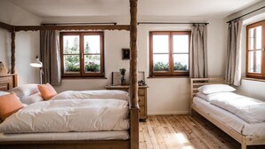 A room with two beds, wooden flooring, and large windows with curtains. - Berghotel Altes Wallberghaus (Rottach-Egern)
