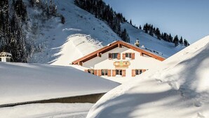 A snow-covered mountain with a wooden chalet in the foreground. - Berghotel Altes Wallberghaus (Rottach-Egern)