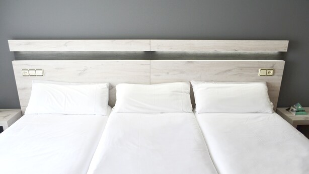 A double bed with white linens and a wooden headboard. - Alda Puerta Coruña (A Coruña)