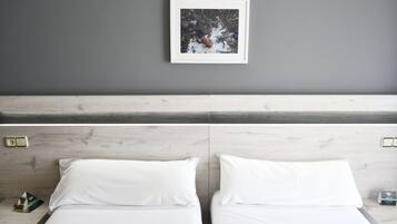 Una habitación de hotel con una pared gris, un cuadro enmarcado sobre la cama y un cabecero de madera.