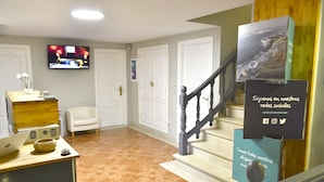 A living room with a TV, a laptop, a chair, and a staircase. - Alda Puerta Coruña (A Coruña)
