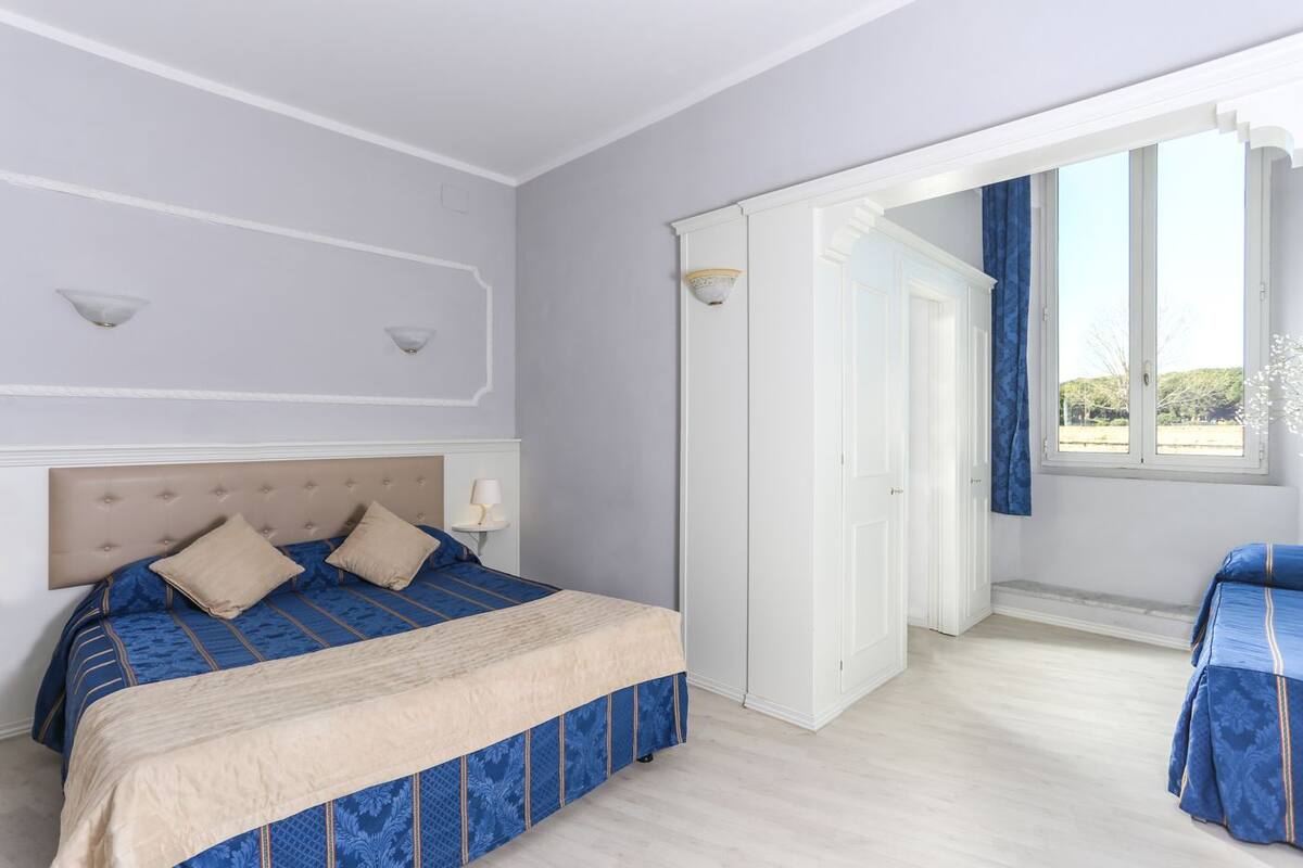 Ein Schlafzimmer mit Bett, Nachttischen, einem Kleiderschrank und einem Fenster mit Vorhängen.