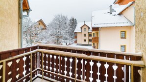 A balcony with a wooden railing featuring heart-shaped cutouts, overlooking a snow-covered residential area with houses and trees. - Apartamenty Sun & Snow Osiedle Podgórze (Szklarska Poreba)