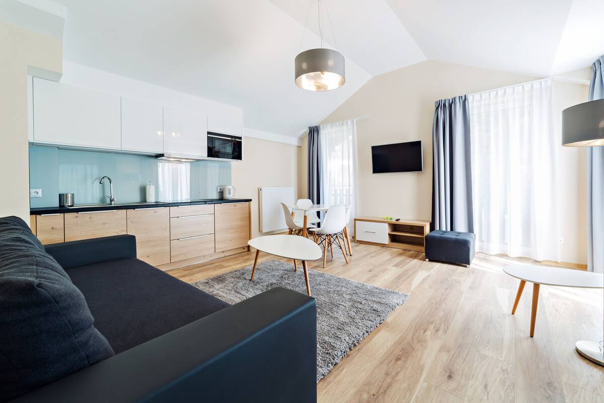 Ein modernes Wohnzimmer mit einer Couch, einem Esstisch und einer Küchenzeile mit einer Mikrowelle.