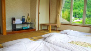 A traditional Japanese room with tatami flooring, a low wooden table, and a view of a lush green landscape through the window.