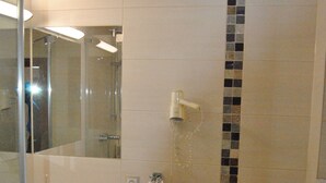 A bathroom with a sink, mirror, towel rack, toilet, and a shower area. - Hotel Zur Sonne (Herrieden)