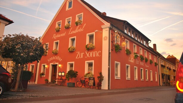 A red building with the sign "Restaurant Landhotel Zur Sonne" and "Sonnentor" on the facade. - Hotel Zur Sonne (Herrieden)