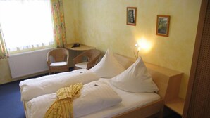 A double bed with white linens, a bedside table with a lamp, a chair, and two framed pictures on the wall. - Hotel Zur Sonne (Herrieden)