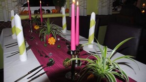 A table set for dining with pink candles, green and white napkins, and a potted plant. - Hotel Zur Sonne (Herrieden)