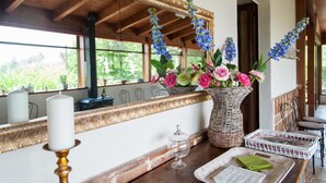 Una mesa de madera con un florero de mimbre lleno de flores, una vela y una bandeja con servilletas.