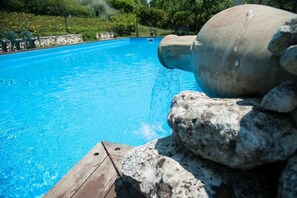 A swimming pool with clear blue water, a concrete pipe, and rocks at the edge. - Agriturismo La Solagna (Montebello di Bertona)