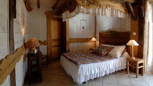 Una habitación rústica de madera con una cama, dos lámparas y una puerta.