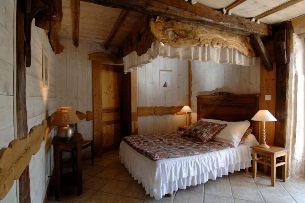 Una habitación rústica de madera con una cama, dos lámparas y una puerta.