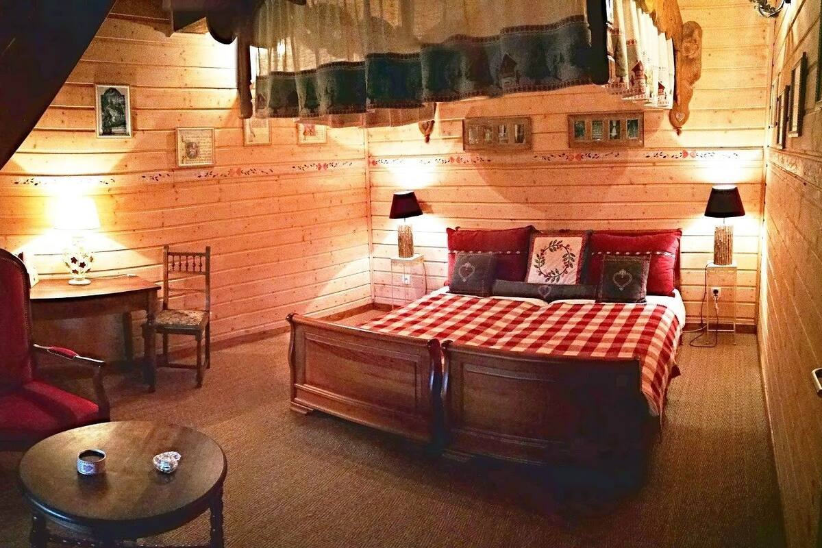 Una habitación acogedora con una cama, una silla, una mesita y una lámpara.
