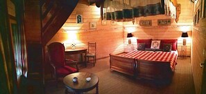A cozy room with a bed, a chair, a small table, and a lamp. - La Ferme Bonne de la Grotte (Saint-Christophe-la-Grotte)