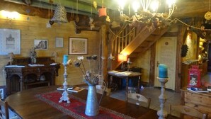 Un interior rústico con una mesa de comedor de madera, un candelabro y una escalera.