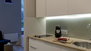 A modern kitchen with a coffee maker, a cutting board with vegetables, and a sink. - Apartamenty 2M (Czestochowa)