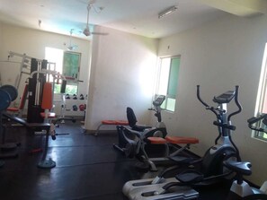Une salle de sport équipée de divers appareils d’exercice, notamment un tapis de course, des vélos d’appartement et des appareils de musculation.