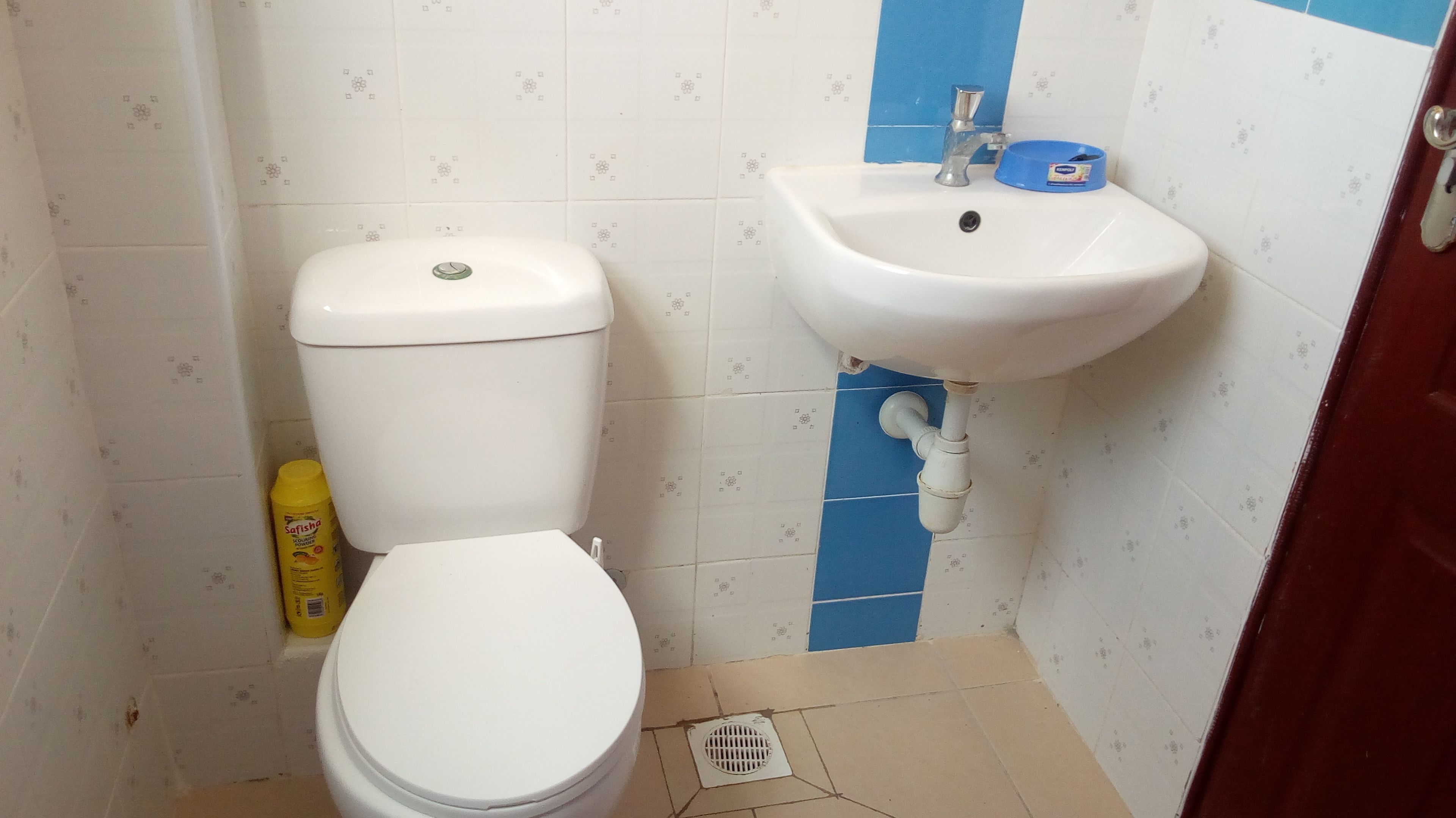 A small bathroom with a toilet, sink, and blue and white patterned tiles.
