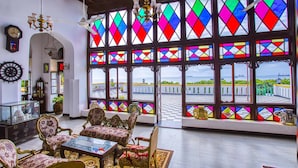 Una stanza con mobili decorati, un'ampia finestra con vetrate colorate e vista sul mare.