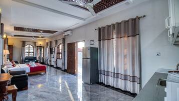 Habitación de hotel con cama, escritorio, silla, refrigerador y baño con ducha.