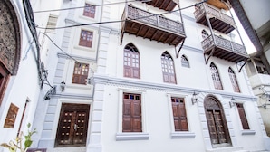 Un edificio bianco con numerose finestre e porte, caratterizzato da persiane in legno e balconi.