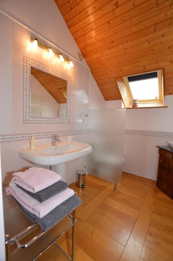 Une salle de bain avec un plafond en bois, un lavabo, un miroir et une fenêtre.