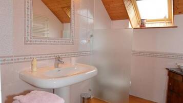 Un baño con techo de madera, un lavabo, un espejo y una ventana.