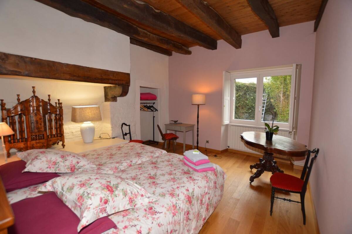 A bedroom with a bed, bedside tables, a desk, and a window.