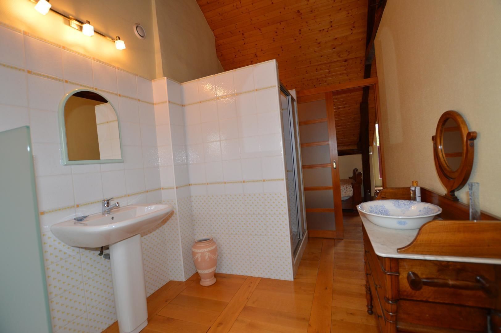 Een badkamer met een houten plafond, een wastafel, een spiegel en een toilet.