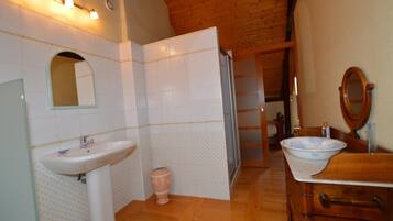 Een badkamer met een houten plafond, een wastafel, een spiegel en een toilet.