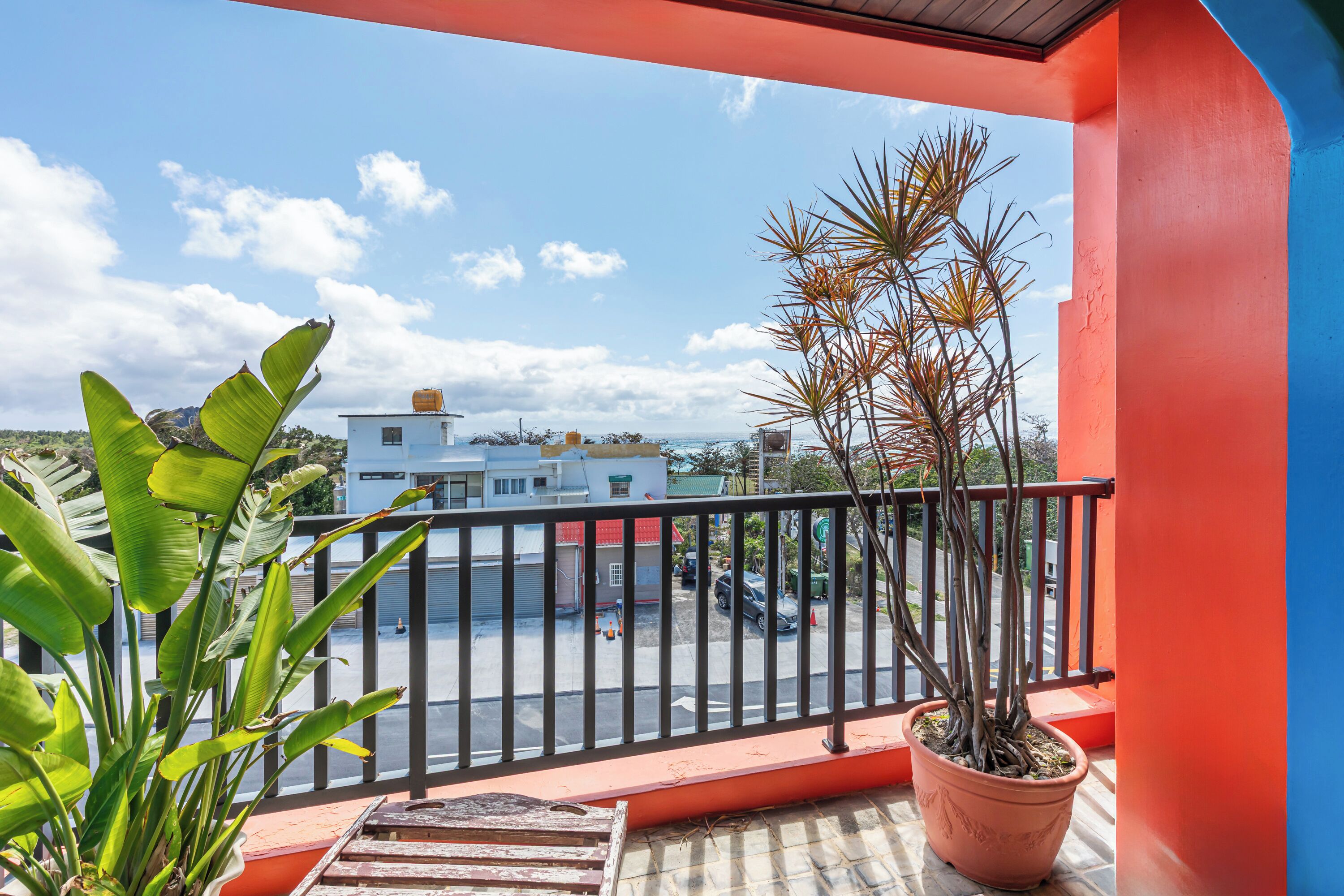 Ein Balkon mit einem Blumentopf, Blick auf eine Straße und ein Gebäude im Hintergrund.