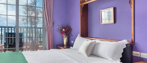 Una cama bien hecha con ropa blanca, un cabecero de madera y un florero sobre una mesita de noche.