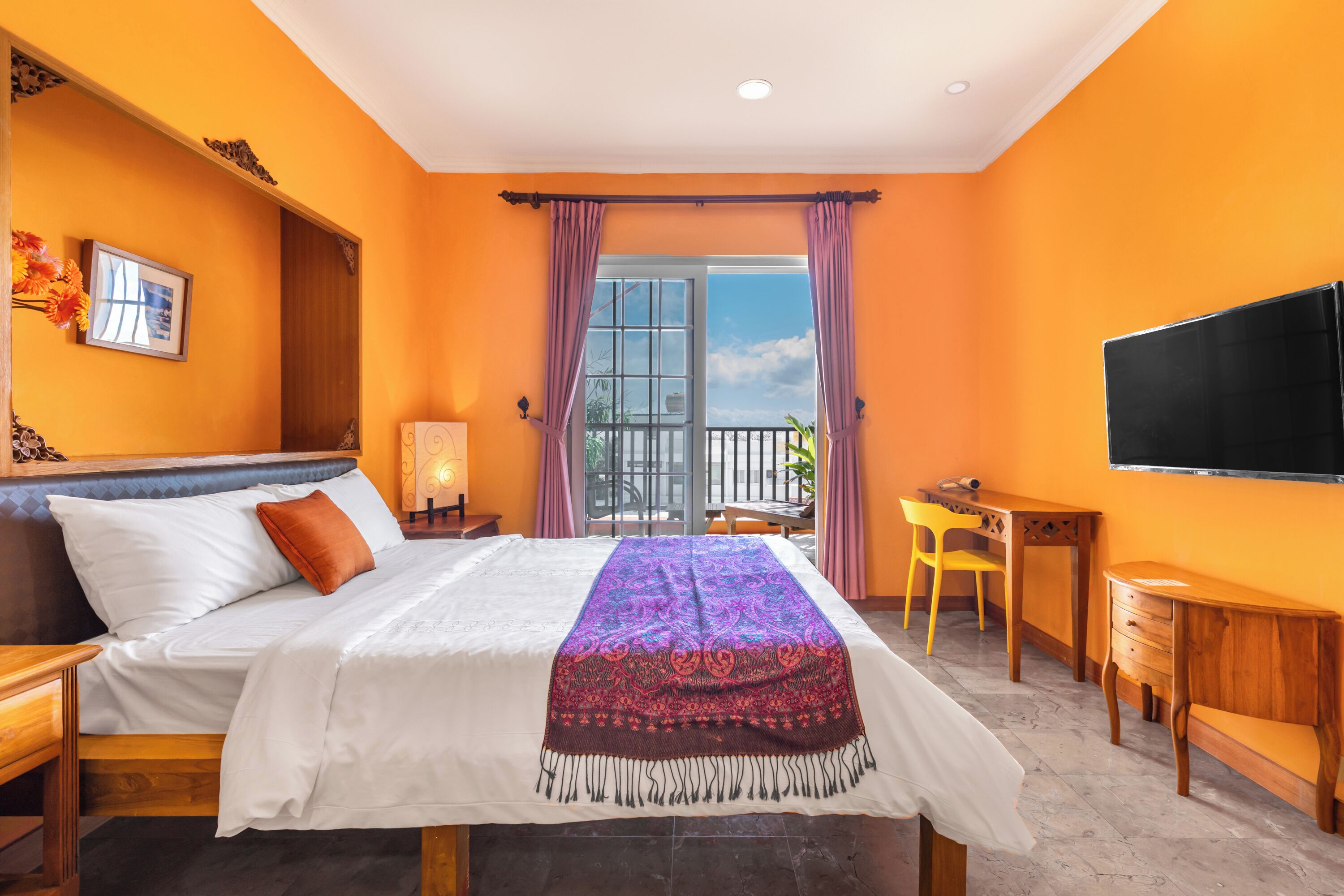 A bedroom with a bed, a desk, a chair, and a TV.