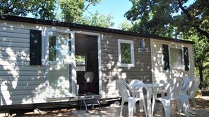 A mobile home with a porch and a table with chairs.
