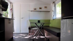A compact kitchen with a table and bench seating, a refrigerator, and a door leading to another room.