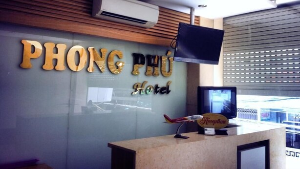 Un comptoir d’accueil avec une pancarte indiquant « Hôtel PHONG PHU » et une maquette d’avion posée sur le comptoir.
