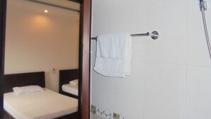 Une chambre d’hôtel avec un lit, une salle de bain avec une douche et une serviette accrochée au mur.