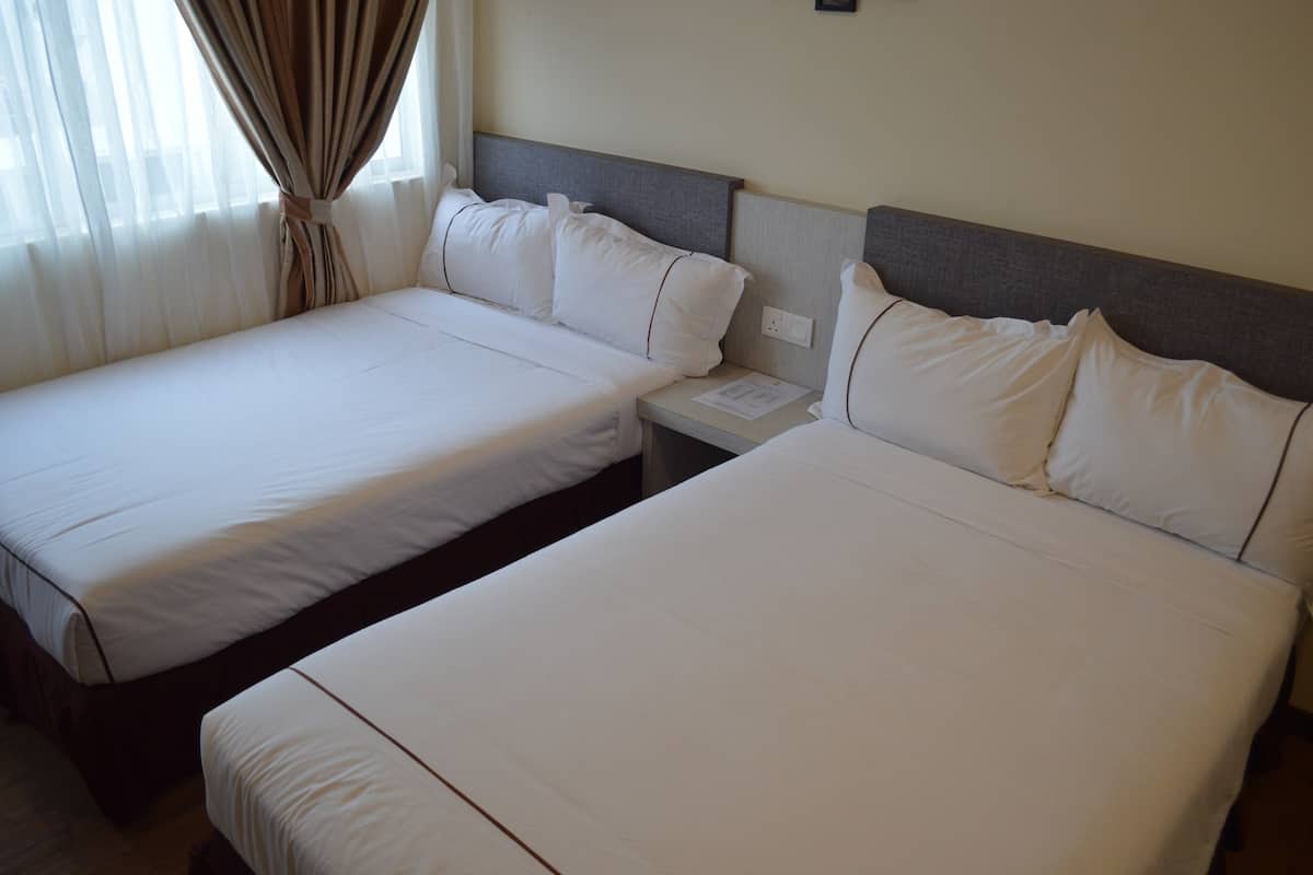 A hotel room with two single beds, a nightstand, and a window with curtains.