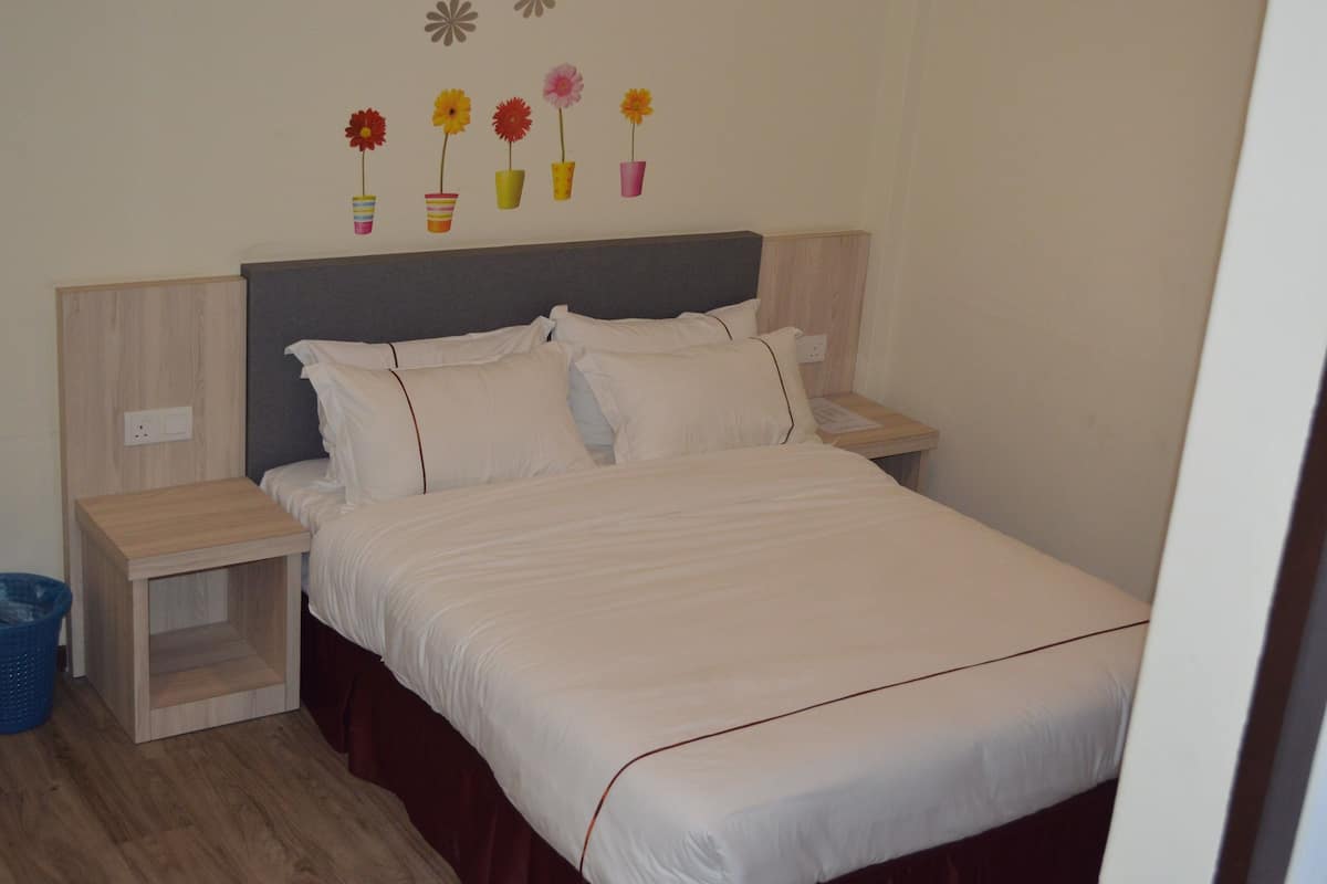 A neatly made bed with white bedding, a wooden headboard, and a nightstand with a lamp.
