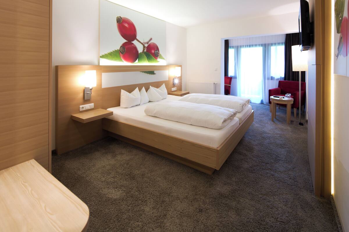 A hotel room with a large bed, bedside tables, a desk, and a chair.