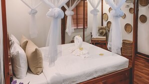 A neatly made bed with white linens, a canopy, and decorative pillows. - Ariya Resort (Koh Rong)