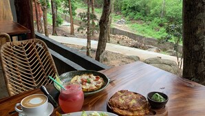 A table with a meal, a drink, and a view of a forested area. - Ariya Resort (Koh Rong)