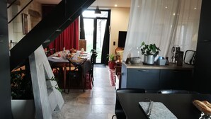 Une cuisine moderne avec un coin repas, comprenant un escalier, une table à manger dressée avec des assiettes et des verres, et une plante en pot posée sur le comptoir.